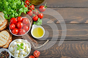 Italian food ingredients Ã¢â¬â mozzarella, tomatoes, basil and olive oil on rustic wooden table.